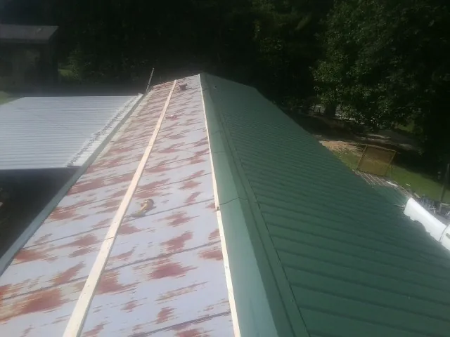 Old rusted panels beside newly installed green metal roofing — Wind Damage Roof Repair by Roofing Brothers in Rock Creek