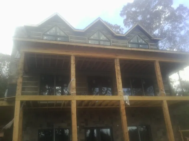 Dormers and porch framing on a large log home under construction — Roof Coating work by our crew in Rock Creek