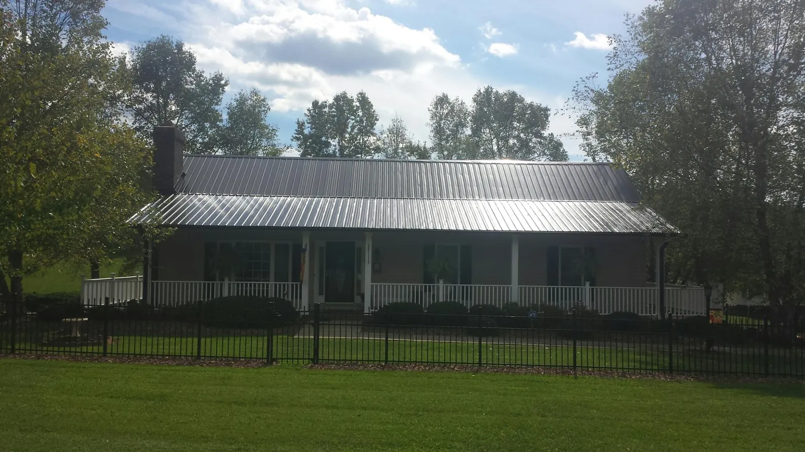 Gray metal roof on a brick ranch with a full width front porch — Gutter Guard Installation work by our crew in Rock Creek