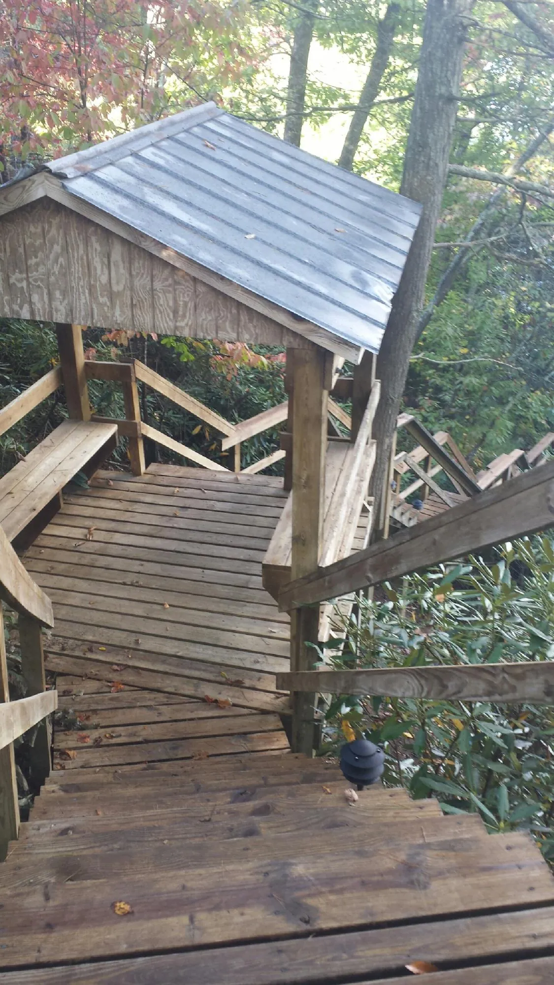 Metal roofed shelter over wooden steps on a wooded walkway — Skylight Repair & Installation work by our crew in Rock Creek