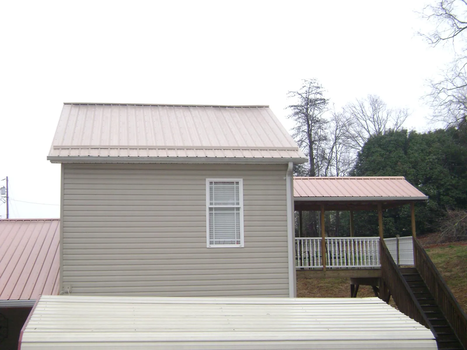 Tan metal roofs on a two story addition and attached porch, from a Roof Replacement job in Rock Creek