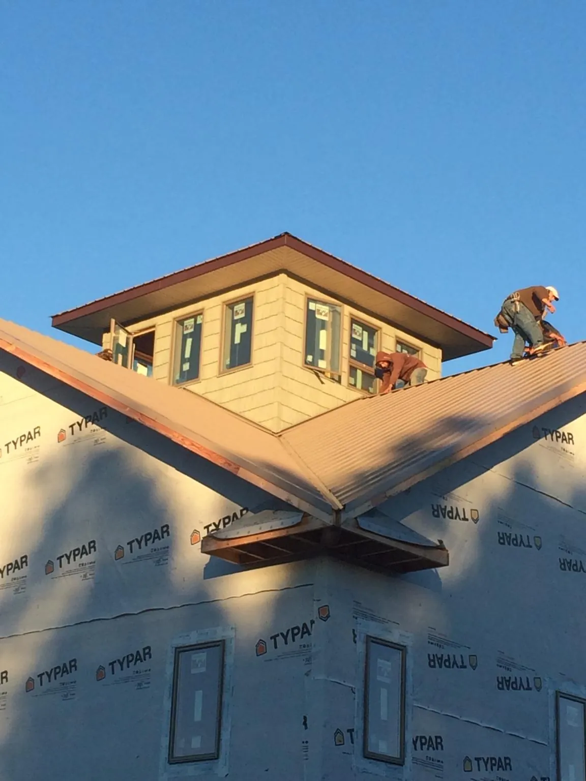 Roofers working around a rooftop cupola on a new metal roof at sunset — Roof Waterproofing in Rock Creek by Roofing Brothers